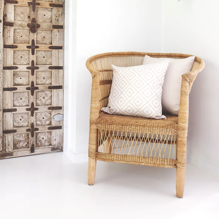 A beige wicker chair hosts two outdoor cushions