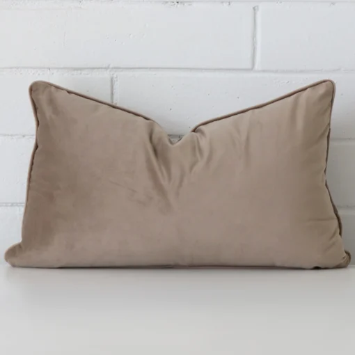 Bold rectangle oyster cushion positioned in front of white brickwork. It is made from velvet fabric.