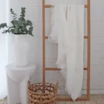 A wooden rack with a white linen throw hanging on it.