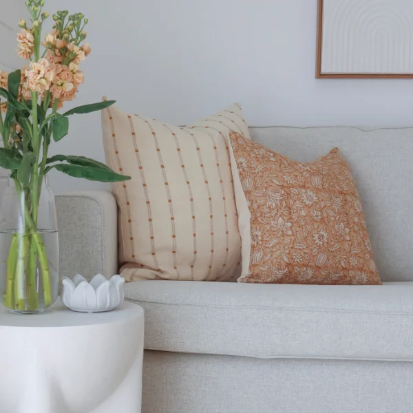 Two lounge cushions styled with a vase of flowers nearby.