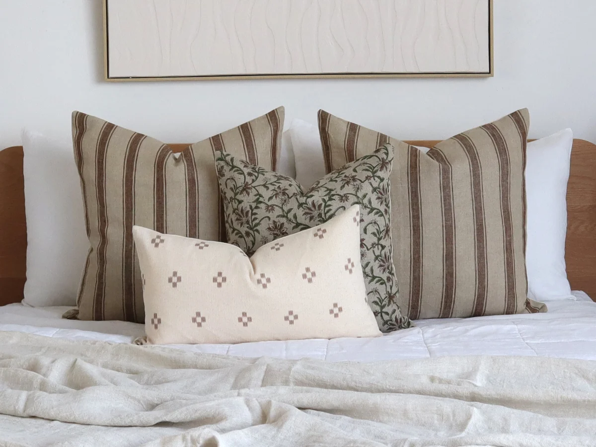 A bed styled with cushions. Featuring two large designs at the rear and smaller designs in the front.