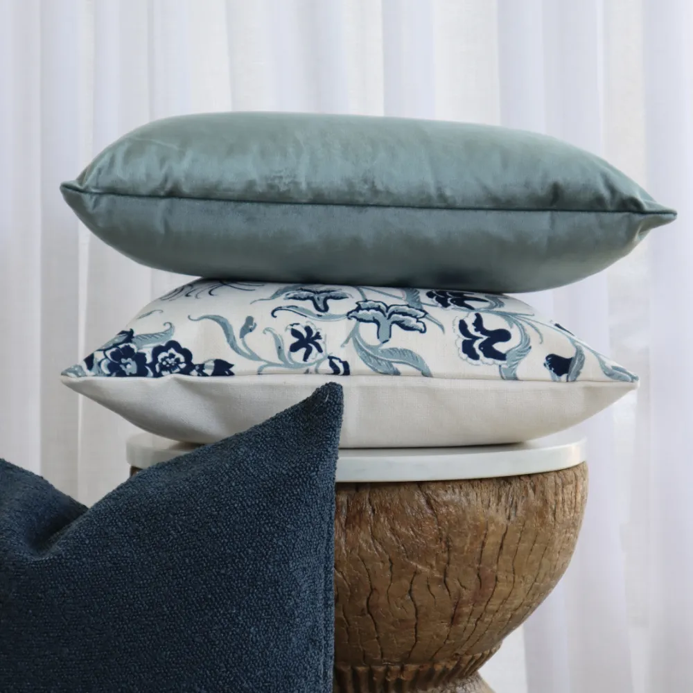 Some classic cushion sets stacked on a wooden table.