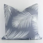 An attractive outdoor cushion in front of a white wall. It has a square shape and is grey in colour.