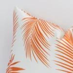 A rectangle orange outdoor cushion cover’s corner is shown in more detail. It is possible to see the palm decorative finish in much more detail.