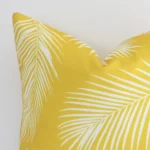 Macro image of an outdoor square cushion cover. The shot shows the yellow hue and palm style more thoroughly.