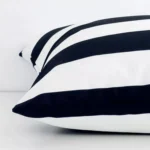 Lateral angle image of a outdoor large cushion. The black and white colour and striped design are highlighted along its seams.