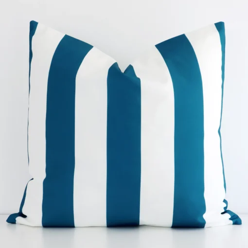 A large striped cushion in a delightful teal tone rests against a white wall. The outdoor material appears to be of exceptional quality.