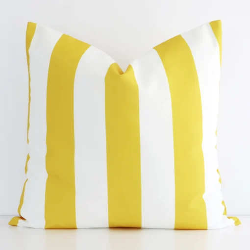 An outdoor large cushion cover that has a unique striped design is shown vertically against a white wall. It has a wonderful yellow colour.