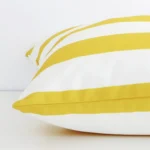 A side shot of a striped outdoor cushion cover. The angle shows the edge of the large shape and the yellow tone.