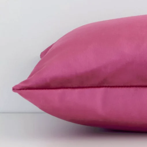 Horizontal edge of solid-coloured rectangle cushion cover is shown. The velvet fabric and blush tone can be seen from this side view.