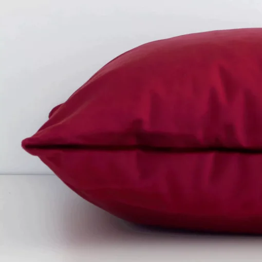 The seams of this velvet square cushion cover in solid-coloured burgundy are shown. The image shows how the panels are attached.