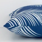 Horizontal edge of palm styled square cushion cover is shown. The outdoor fabric and blue tone can be seen from this side view.