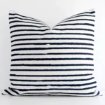 Linen large cushion with a stripe design in an upright position against a white wall.