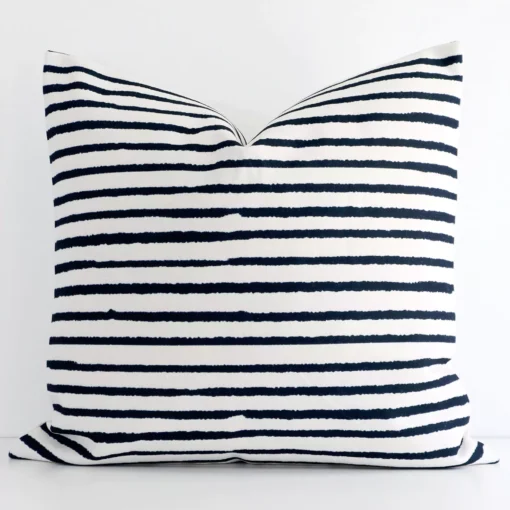 Linen large cushion with a stripe design in an upright position against a white wall.