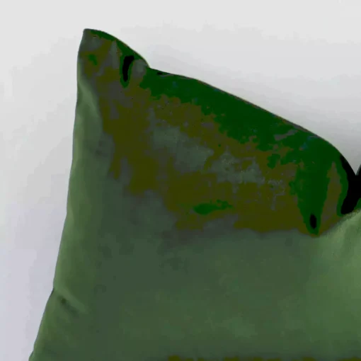 A zoomed view of this velvet forest green cushion’s corner that shows a magnified view of its solid-coloured design and its square size.