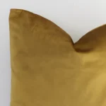 A magnified shot of a solid-coloured velvet cushion cover in a square size and a gold mustard colour.