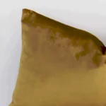 Close up of a velvet rectangle cushion in gold mustard. The quality of its solid-coloured design is shown in fine detail.