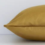 A rectangle velvet cushion positioned flat to show its seams. It has a solid gold mustard colour.