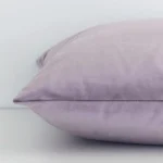 A side shot of a solid-coloured velvet cushion cover. The angle shows the edge of the square shape and the lavender tone.