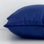 A side view of royal blue cushion that has velvet fabric and a square shape.