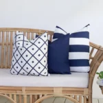 A set of 3 Byron navy outdoor cushions are displayed on a rattan seat.