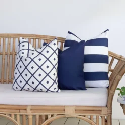 A set of 3 Byron navy outdoor cushions are displayed on a rattan seat.