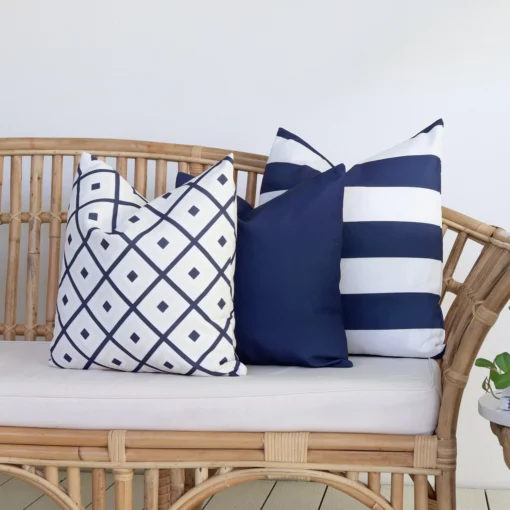 A set of 3 Byron navy outdoor cushions are displayed on a rattan seat.